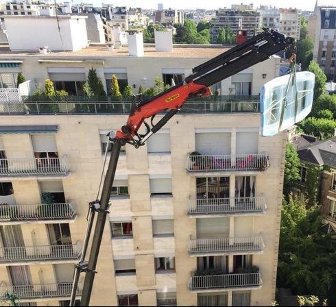 grue transportant un objet lourd au dernier étage d'un immeuble